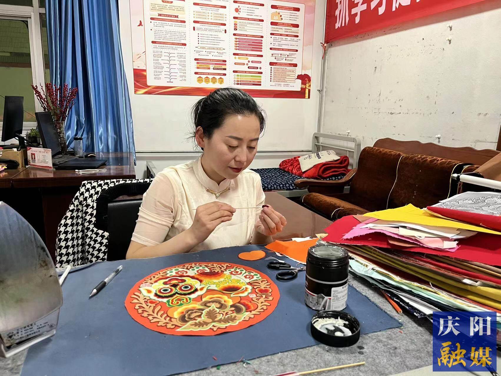李慶英正在創(chuàng)作布貼畫作品。